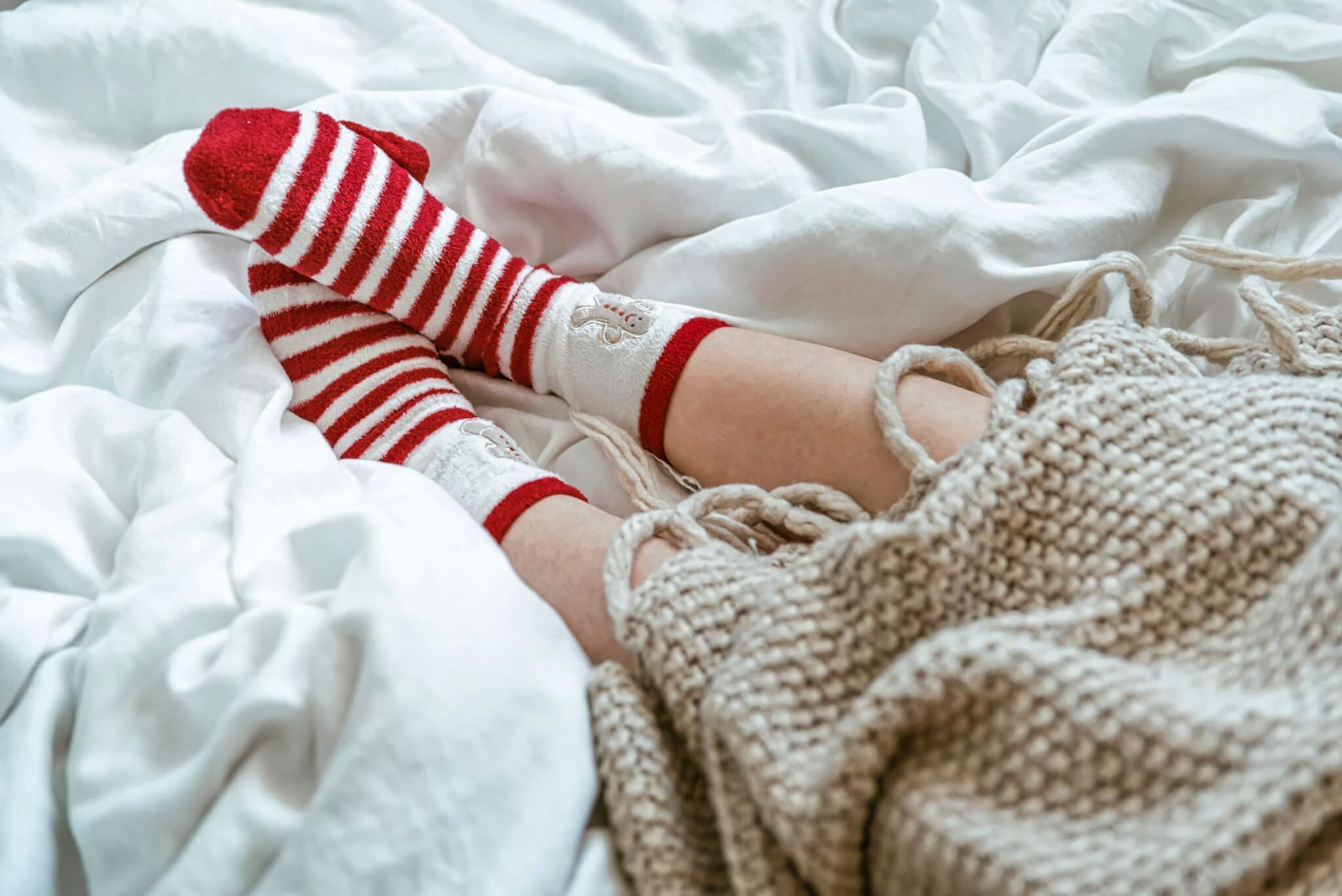 Woman wearing warm red socks in bed. Cozy winter day